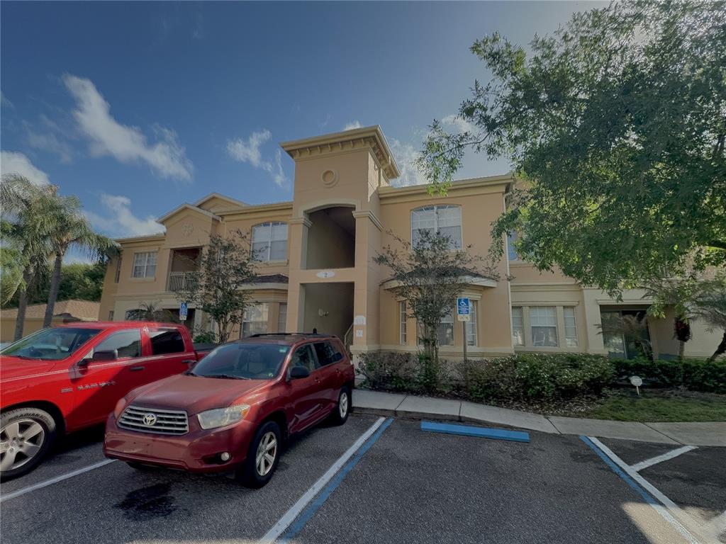 A multi-story apartment building exterior with a parking lot and two parked cars — 204 TERRACE RIDGE CIRCLE UNIT 204, DAVENPORT, FL
