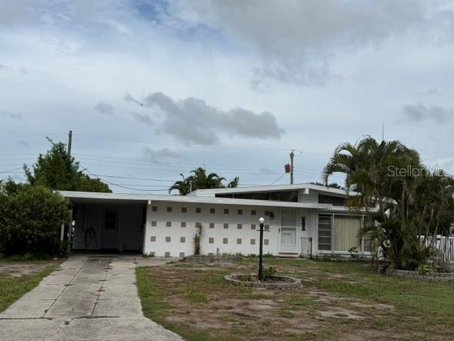 A single-story house with a white facade, a carport, and a palm tree in the yard — 1205 PRINCETON AVENUE, BRADENTON, FL