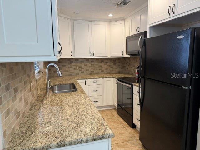 A kitchen features white cabinets, granite countertops, a stainless steel sink, and black appliances — 1205 PRINCETON AVENUE, BRADENTON, FL