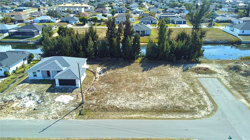 An aerial view shows a vacant residential lot next to a newly constructed house — 122 NE 9TH STREET, CAPE CORAL, FL