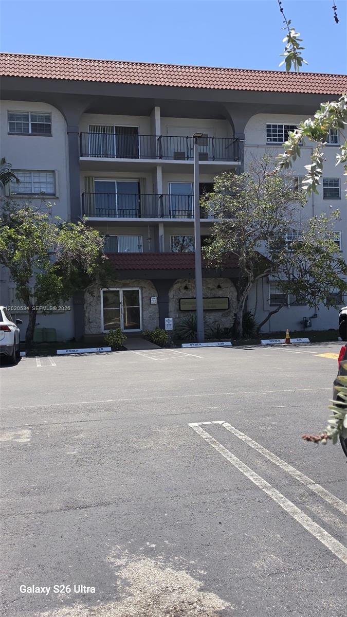 A three-story apartment building with balconies and a parking lot in the foreground — 8107 SW 72nd Ave # 423E, Miami FL 33143, MIAMI, FL