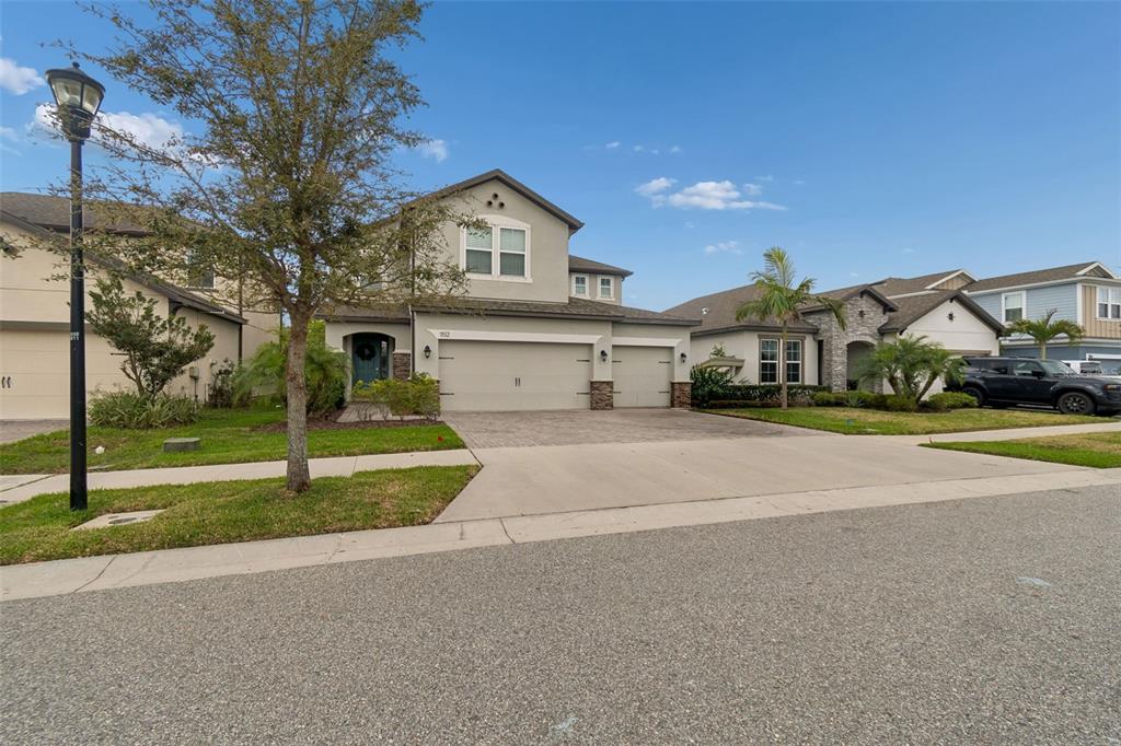A two-story suburban house with a paved driveway, three-car garage, and a landscaped front yard — 11512 NAVEL ORANGE WAY, TAMPA, FL