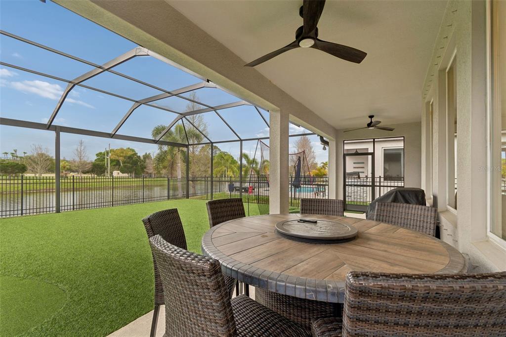 A backyard patio with artificial turf, a putting green, and a screened-in enclosure — 11512 NAVEL ORANGE WAY, TAMPA, FL