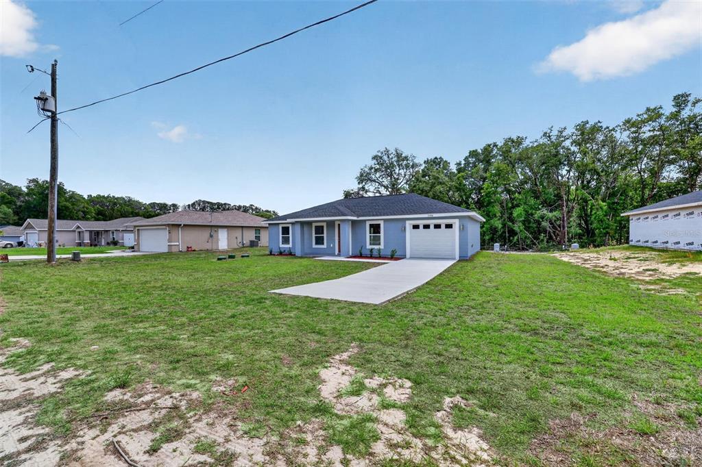 A blue single-story house with a white garage and a concrete driveway sits on grass — 13914 SW 104TH LANE, DUNNELLON, FL