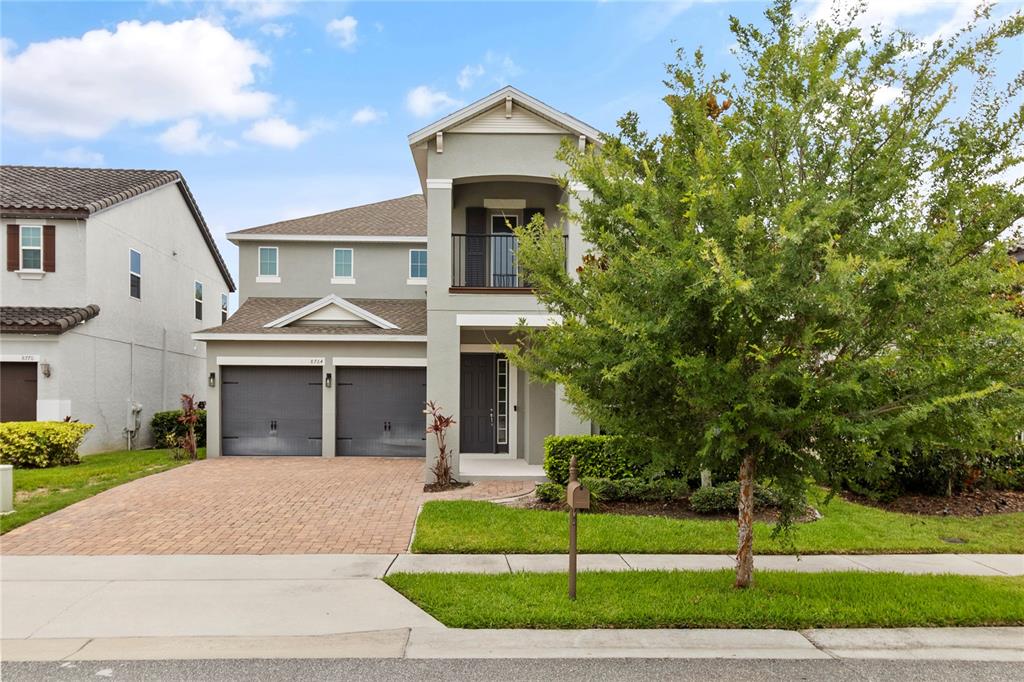 A two-story suburban house with a gray stucco exterior, a two-car garage, and a balcony — 8764 POWDER RIDGE TRAIL, WINDERMERE, FL