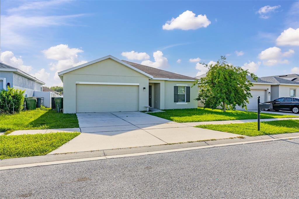 A single-story suburban house with a light-colored exterior, a two-car garage, and a front lawn — 573 LUCERNE BOULEVARD, WINTER HAVEN, FL