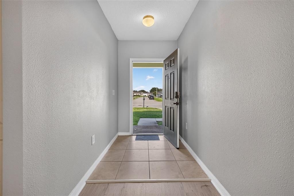 An entryway with light gray walls, tile flooring, and an open door revealing a neighborhood street — 573 LUCERNE BOULEVARD, WINTER HAVEN, FL