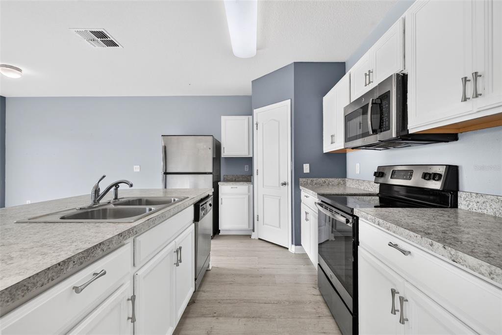 A kitchen features white cabinets, granite countertops, stainless steel appliances, and a central island — 573 LUCERNE BOULEVARD, WINTER HAVEN, FL