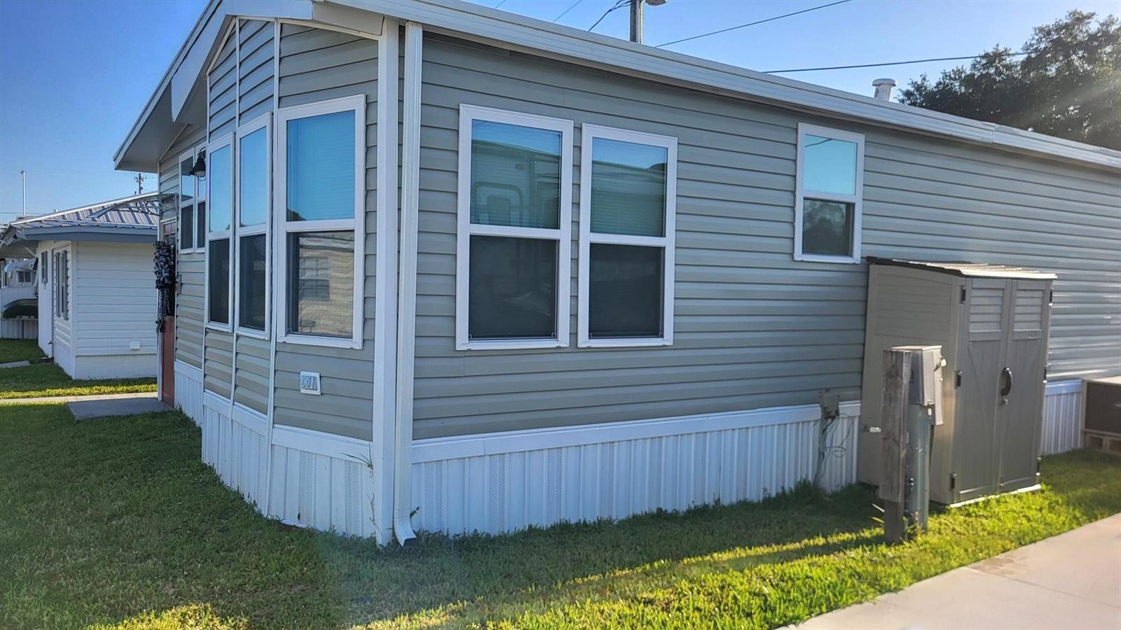 The exterior of a light green manufactured home features white trim, vinyl siding, and a shed — 1339 Old Lakeport Road # 14b, Moore Haven FL 33471, MOORE HAVEN, FL