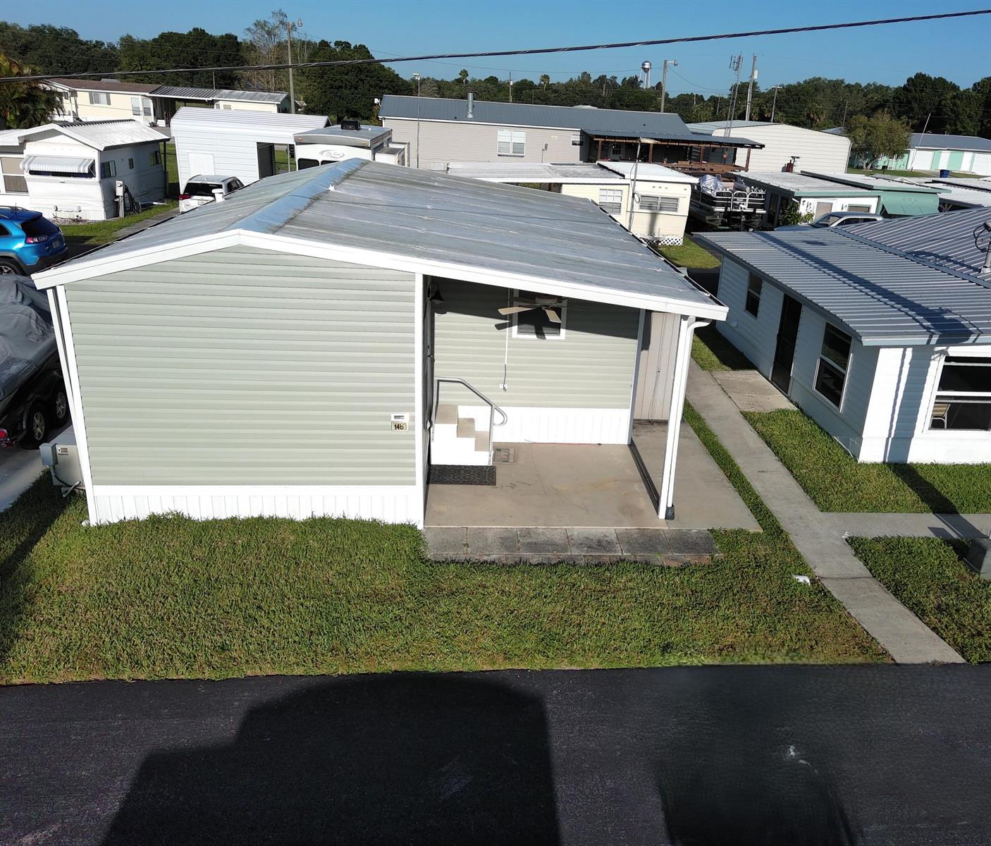 An elevated view of a light green mobile home with a covered porch and walkway — 1339 Old Lakeport Road # 14b, Moore Haven FL 33471, MOORE HAVEN, FL
