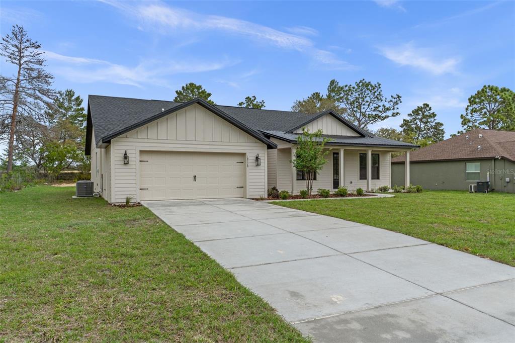 A single-story house with beige siding, a two-car garage, and a concrete driveway — 18178 MABERLY ROAD, WEEKI WACHEE, FL