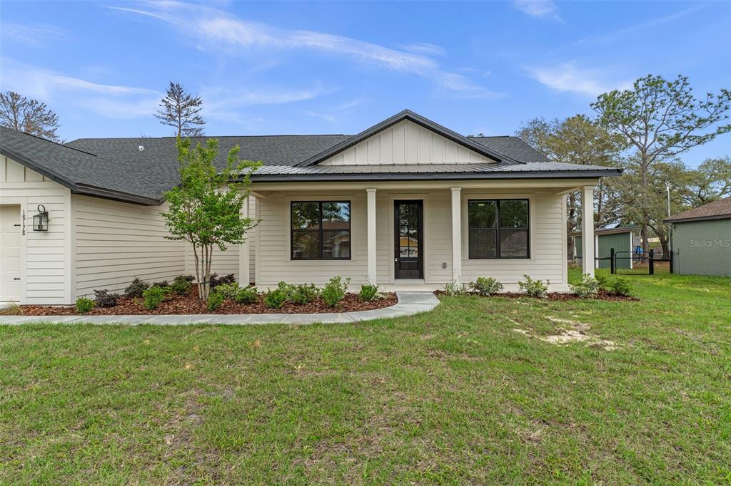 A single-story house with light siding, a covered front porch, and a dark shingled roof — 18178 MABERLY ROAD, WEEKI WACHEE, FL
