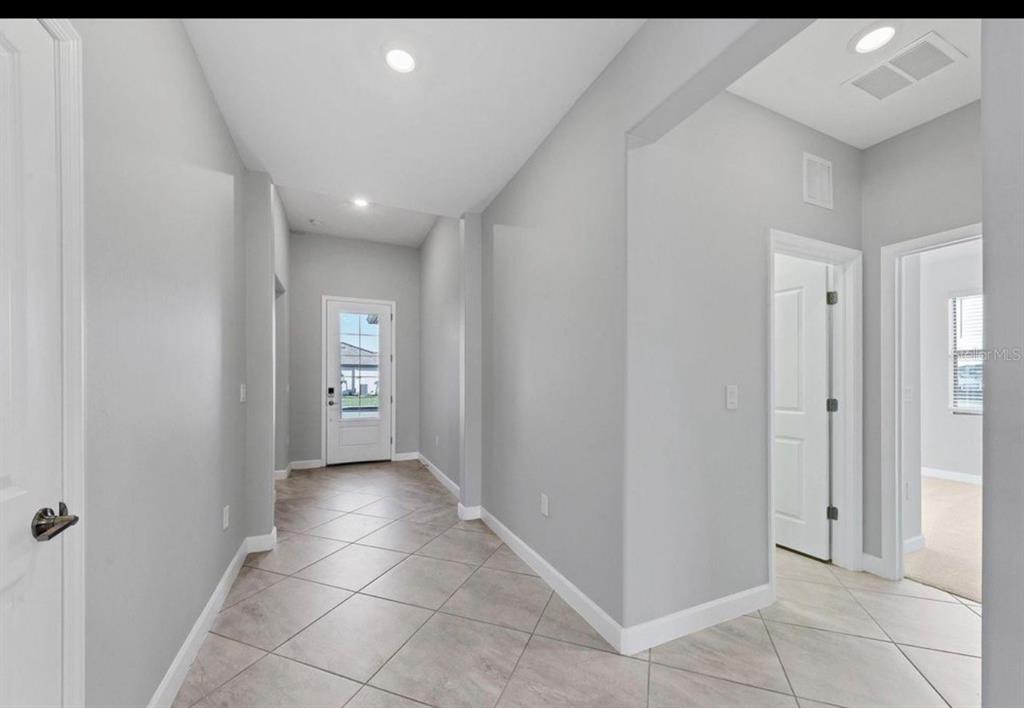 A bright entryway with light gray walls, tile flooring, and a white front door — 5127 CORAL REEF WAY, BRADENTON, FL