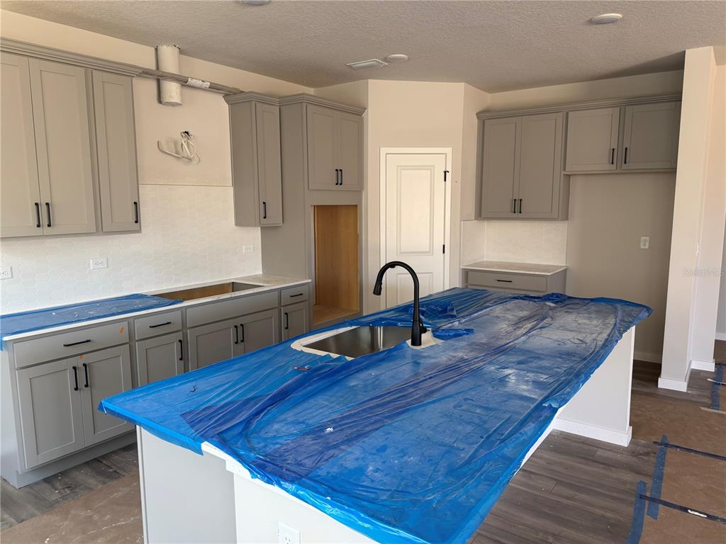 A kitchen under construction features gray cabinets, a large island with a sink, and countertops — 28 PERSEUS AVENUE, FLAGLER BEACH, FL