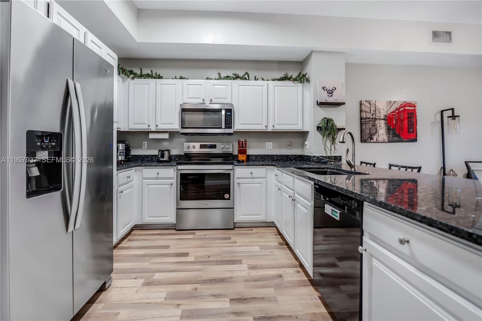 A kitchen with white cabinets and a black island opens into a living area — 7401 Palomino Dr # 1, Davie FL 33024, DAVIE, FL