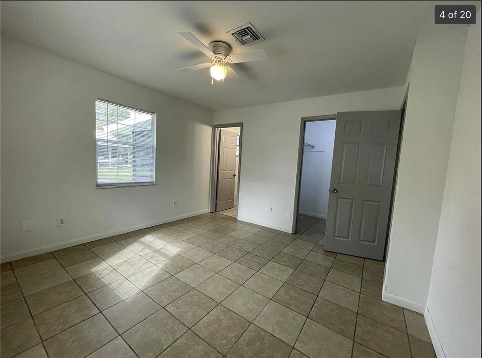 An empty bedroom with white walls, tan tile flooring, a ceiling fan, and two doorways — 2385 88th Avenue, Vero Beach FL 32966, VERO BEACH, FL
