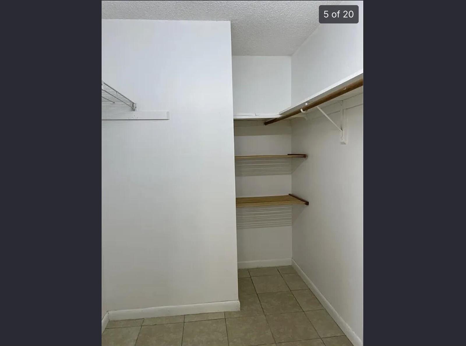 A walk-in closet features white walls, tile flooring, and built-in wooden shelving and rods — 2385 88th Avenue, Vero Beach FL 32966, VERO BEACH, FL