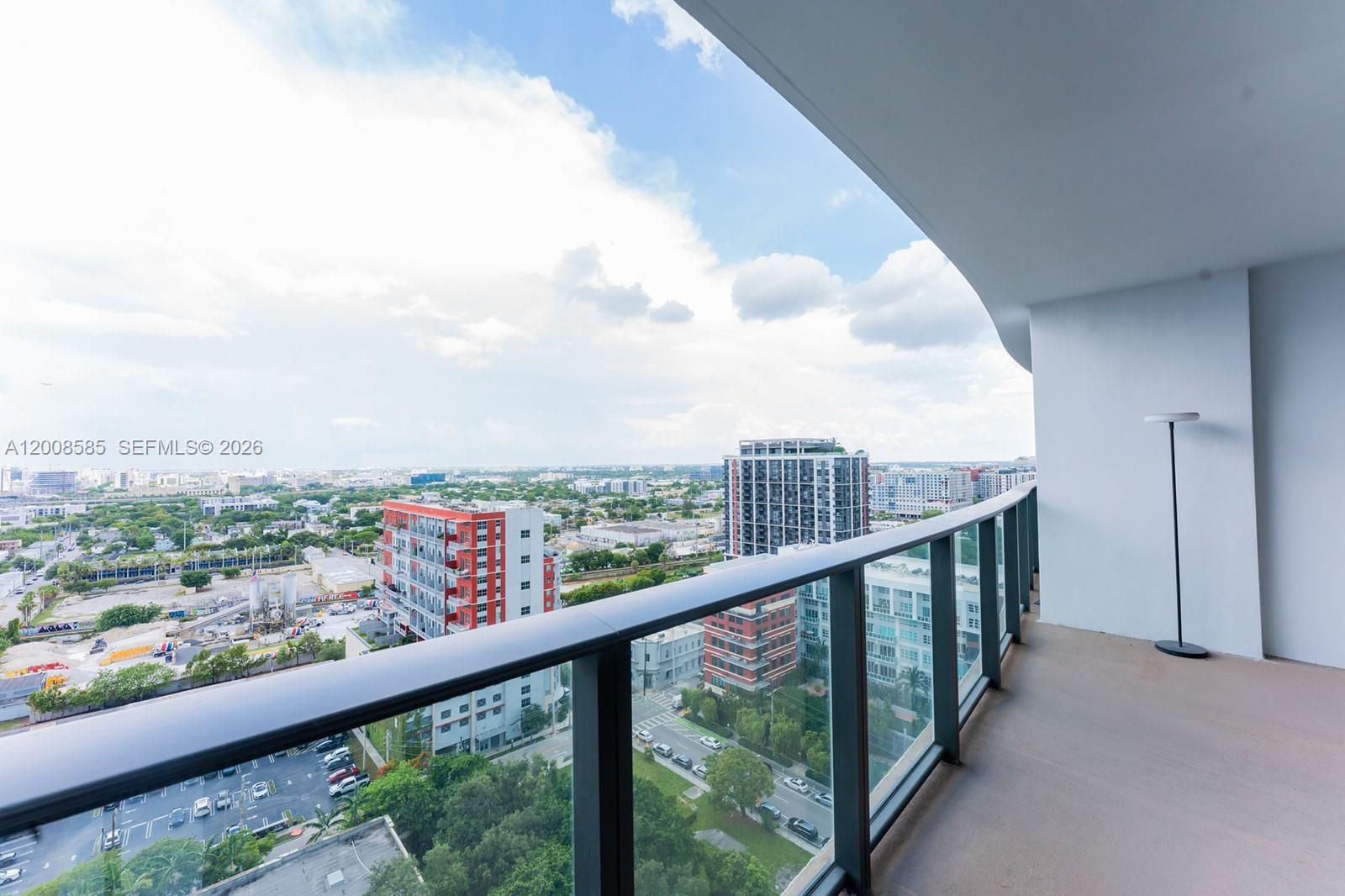 A high-rise balcony features a glass railing overlooking a city skyline and urban landscape — 1600 NE 1st Ave # 1814, Miami FL 33132, MIAMI, FL