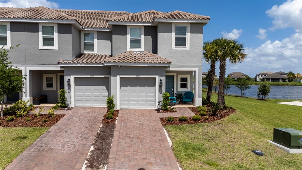 A two-story townhouse with a gray exterior, two garage doors, and a brick driveway — 3635 MAIN HARBOR DRIVE, KISSIMMEE, FL