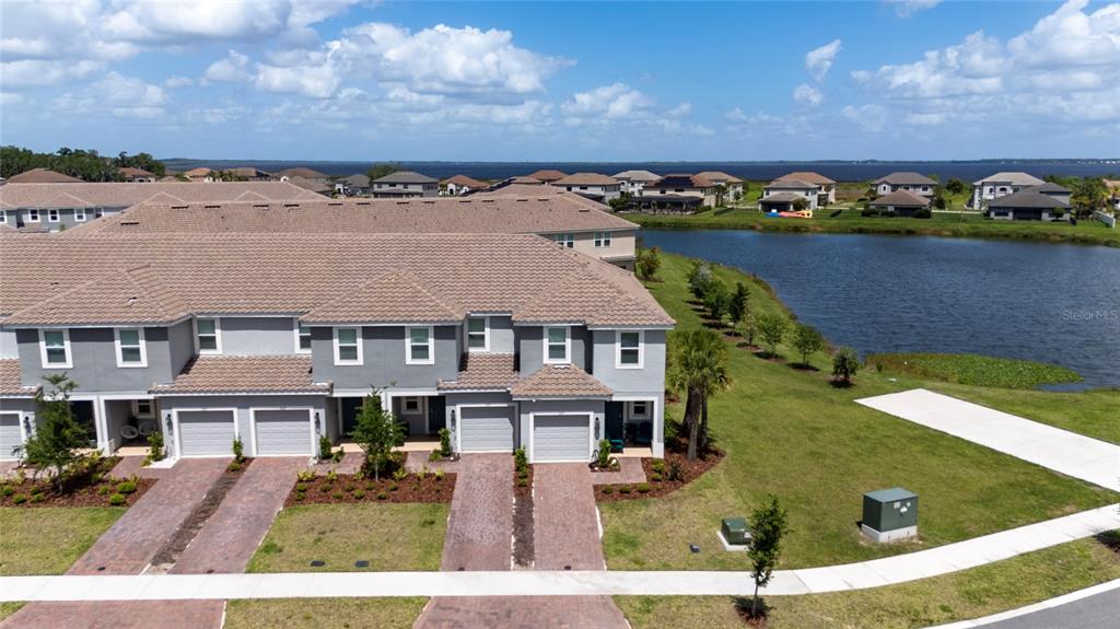 An aerial view of a multi-unit townhouse complex with a lake in the background — 3635 MAIN HARBOR DRIVE, KISSIMMEE, FL