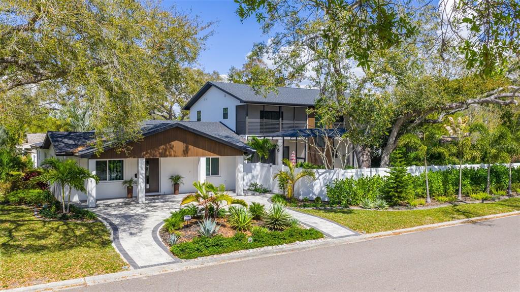 A two-story house with white walls, wood accents, and a paved driveway surrounded by trees — 639 43RD AVENUE N, ST PETERSBURG, FL