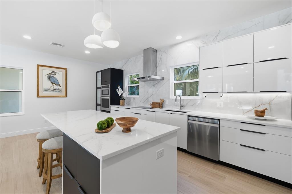 A modern kitchen features white cabinetry, a marble-topped island, and stainless steel appliances — 639 43RD AVENUE N, ST PETERSBURG, FL