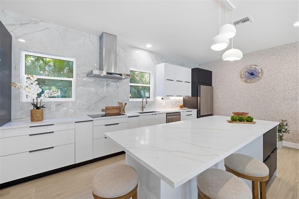 A modern kitchen features white marble countertops, flat-panel cabinets, and a central island with stools — 639 43RD AVENUE N, ST PETERSBURG, FL