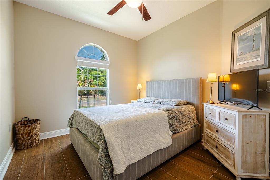 A bedroom features a striped upholstered bed, a wooden dresser, and a large arched window — 1908 W NASSAU STREET, TAMPA, FL