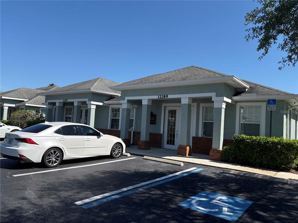 A white sedan is parked in front of a single-story commercial building with green siding — 12187-12189 W LINEBAUGH AVENUE, TAMPA, FL