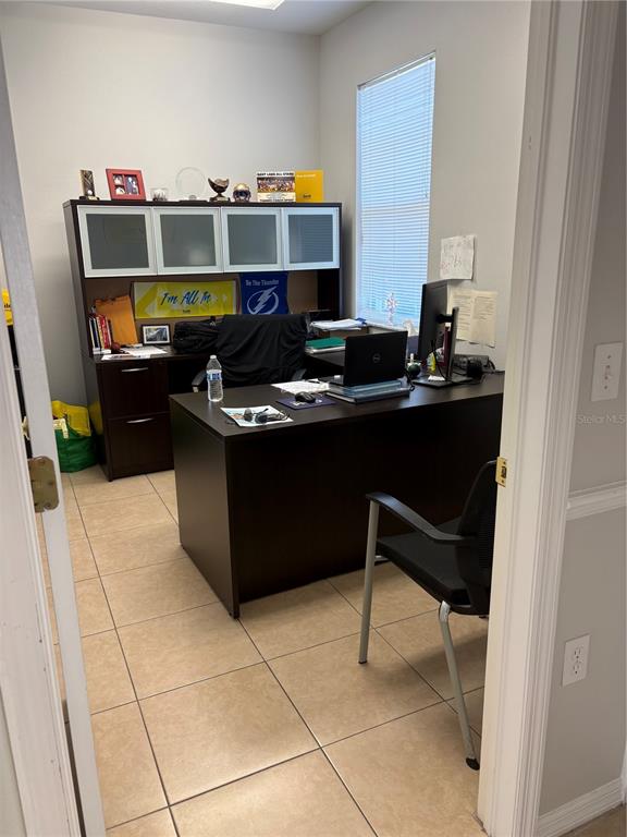 A home office features a dark wood desk, matching hutch, and tile flooring — 12187-12189 W LINEBAUGH AVENUE, TAMPA, FL