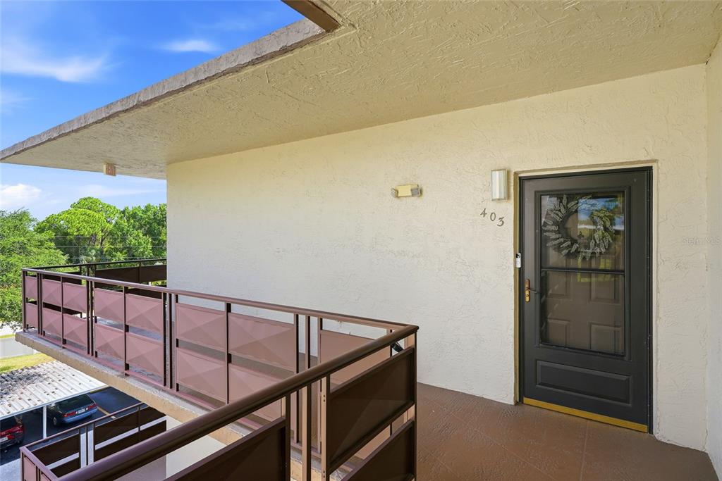 An exterior view of a building balcony with a dark door labeled 403 — 6190 80TH STREET N UNIT 403, ST PETERSBURG, FL