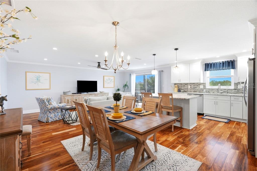 An open-concept dining area and kitchen feature wood flooring, a chandelier, and white cabinetry — 6190 80TH STREET N UNIT 403, ST PETERSBURG, FL