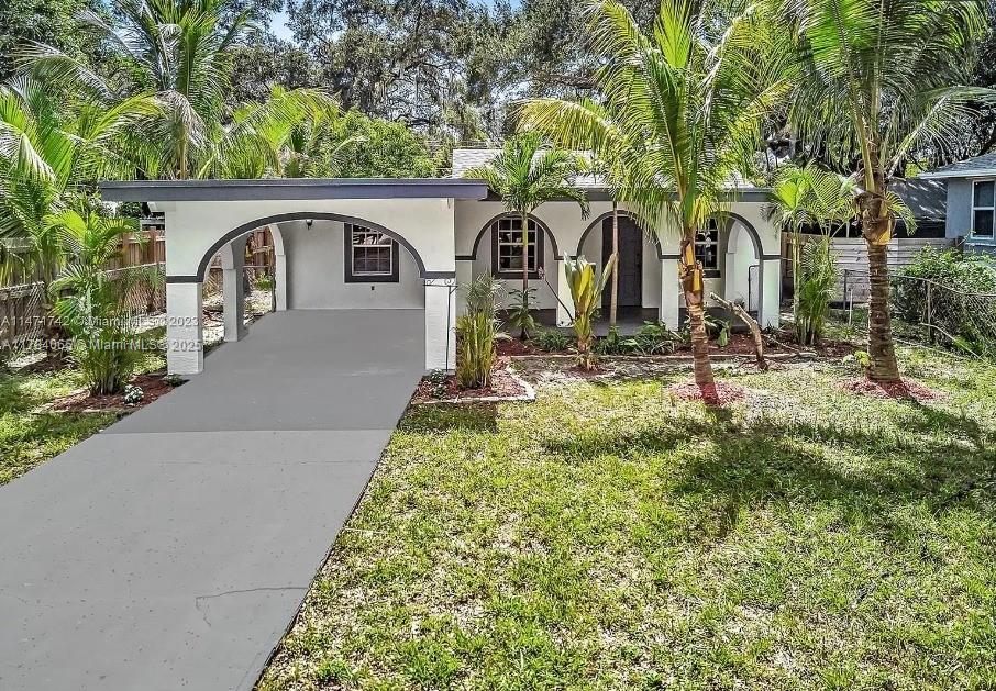 A single-story house features a white stucco exterior, arched entryways, and a concrete driveway — 936 NE 132nd St, North Miami FL 33161, NORTH MIAMI, FL