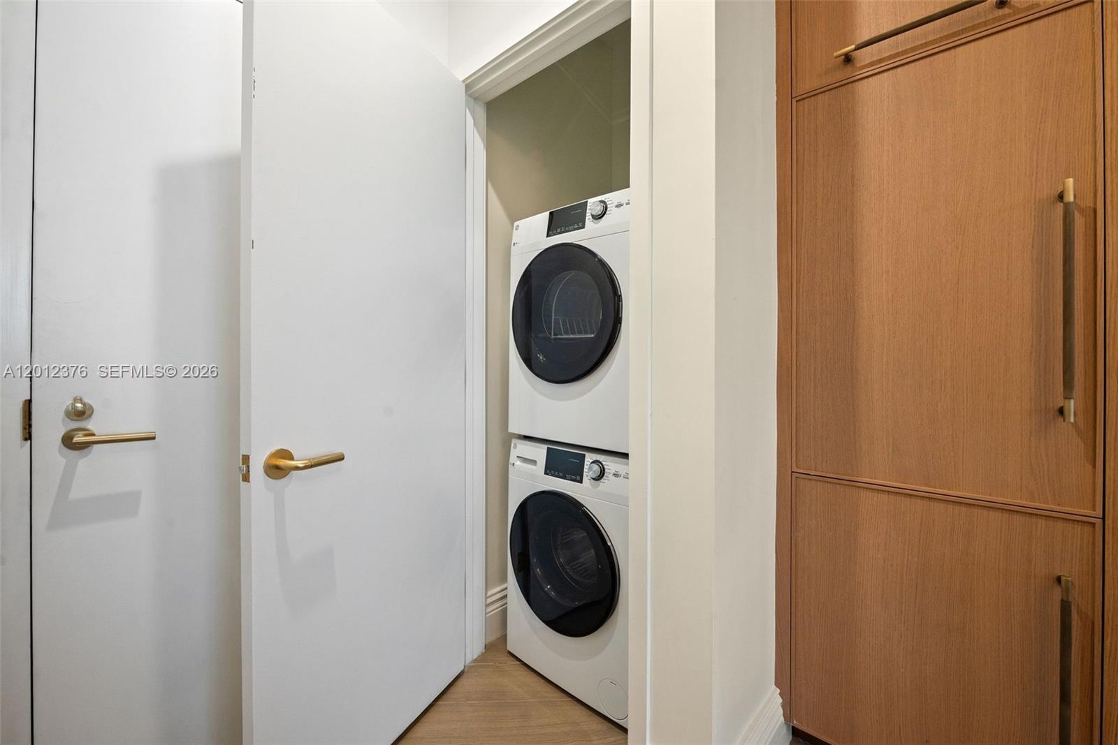 A stacked washer and dryer unit is located in a small closet next to cabinetry — 2700 NW 2nd ave # 708, Miami FL 33127, MIAMI, FL