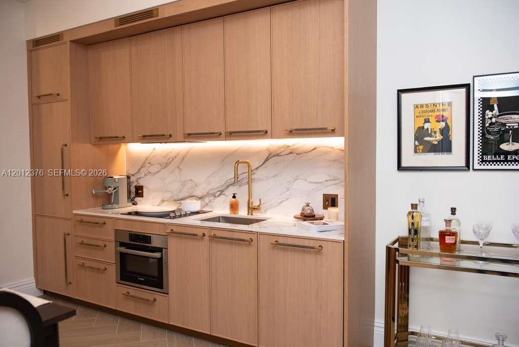 A kitchen features light wood cabinetry, a marble backsplash, and a gold faucet — 2700 NW 2nd ave # 708, Miami FL 33127, MIAMI, FL