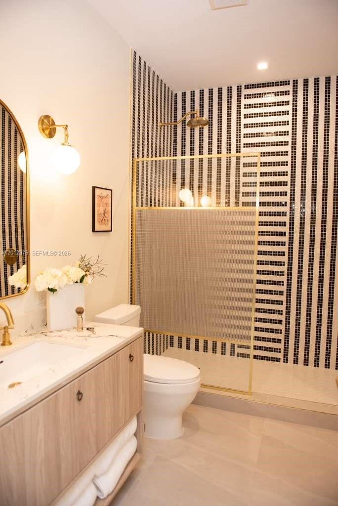 A modern bathroom features a wood vanity, gold fixtures, and a black-and-white striped tiled shower — 2700 NW 2nd ave # 708, Miami FL 33127, MIAMI, FL