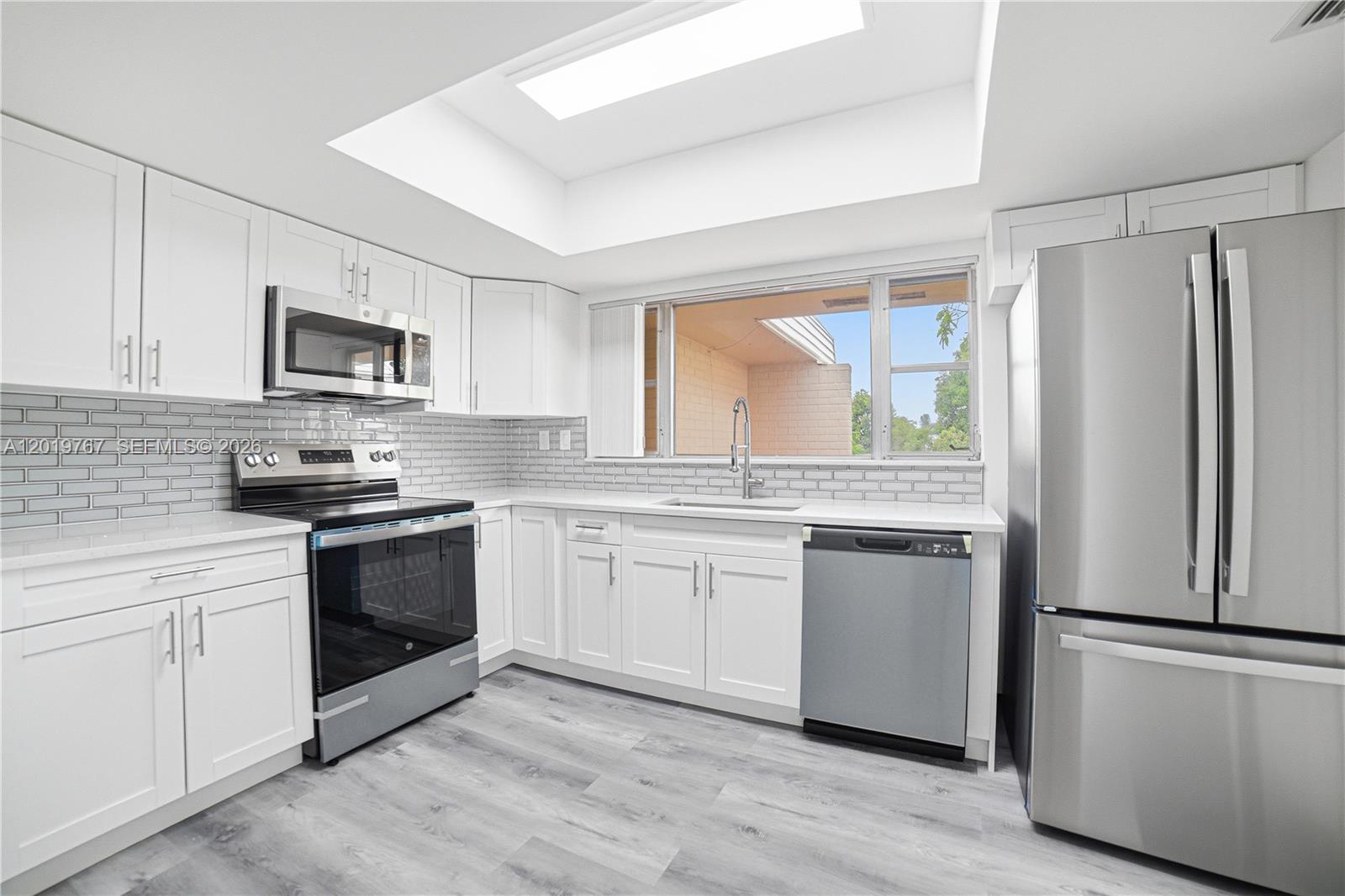 A kitchen features white cabinets, stainless steel appliances, a subway tile backsplash, and a skylight — 5201 Yellow Pine Ln # 0, Tamarac FL 33319, TAMARAC, FL