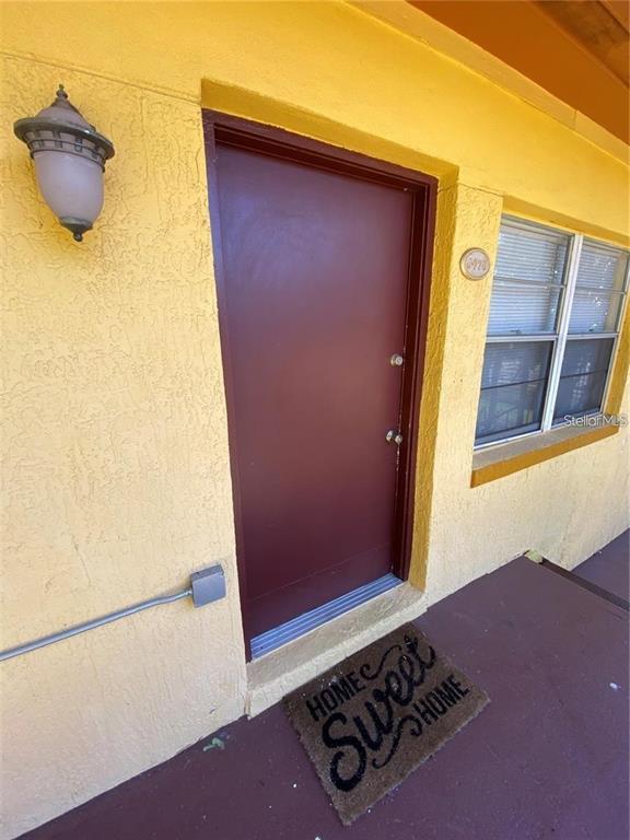A yellow exterior wall features a dark door, a light fixture, and a welcome mat — 778 RIDENHOUR CIRCLE UNIT 778, ORLANDO, FL