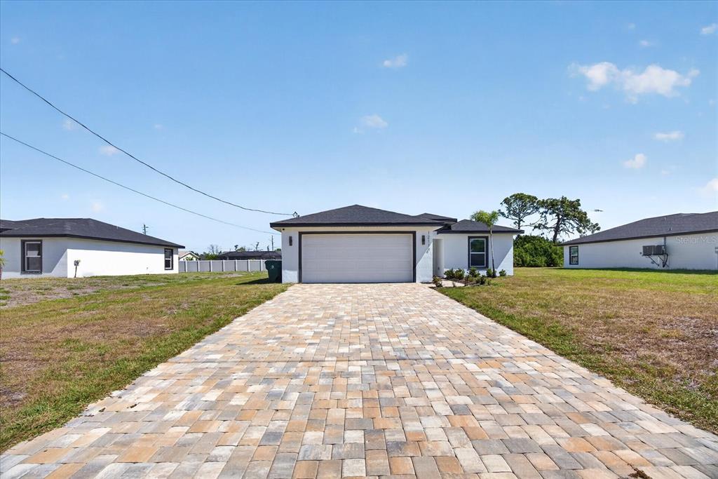A single-story house with a white exterior, dark roof, and a paved driveway — 12114 CLARENDON AVENUE, PORT CHARLOTTE, FL