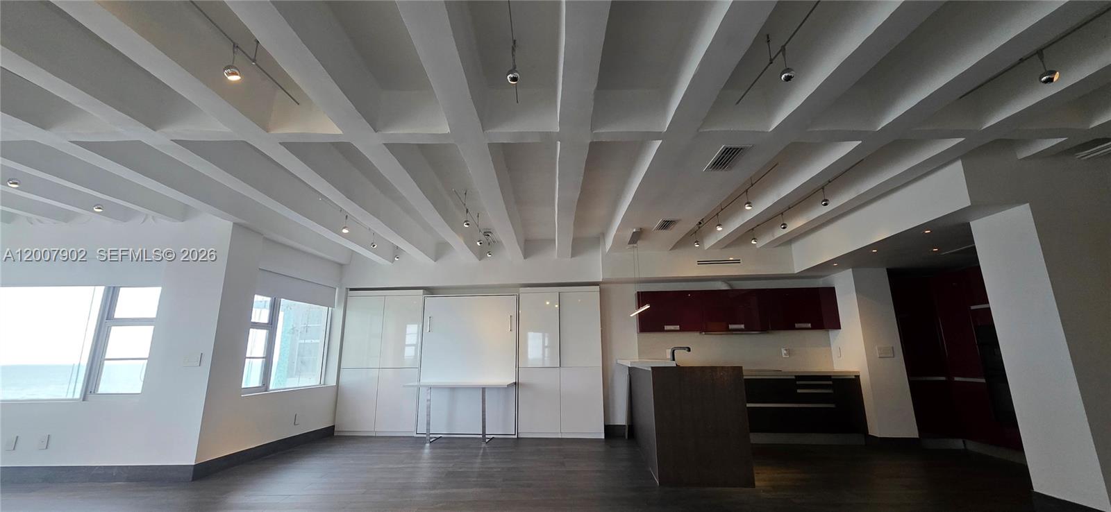 A modern studio apartment features a coffered ceiling, dark wood floors, and a kitchen area — 5255 Collins Ave # 7G, Miami Beach FL 33140, MIAMI BEACH, FL