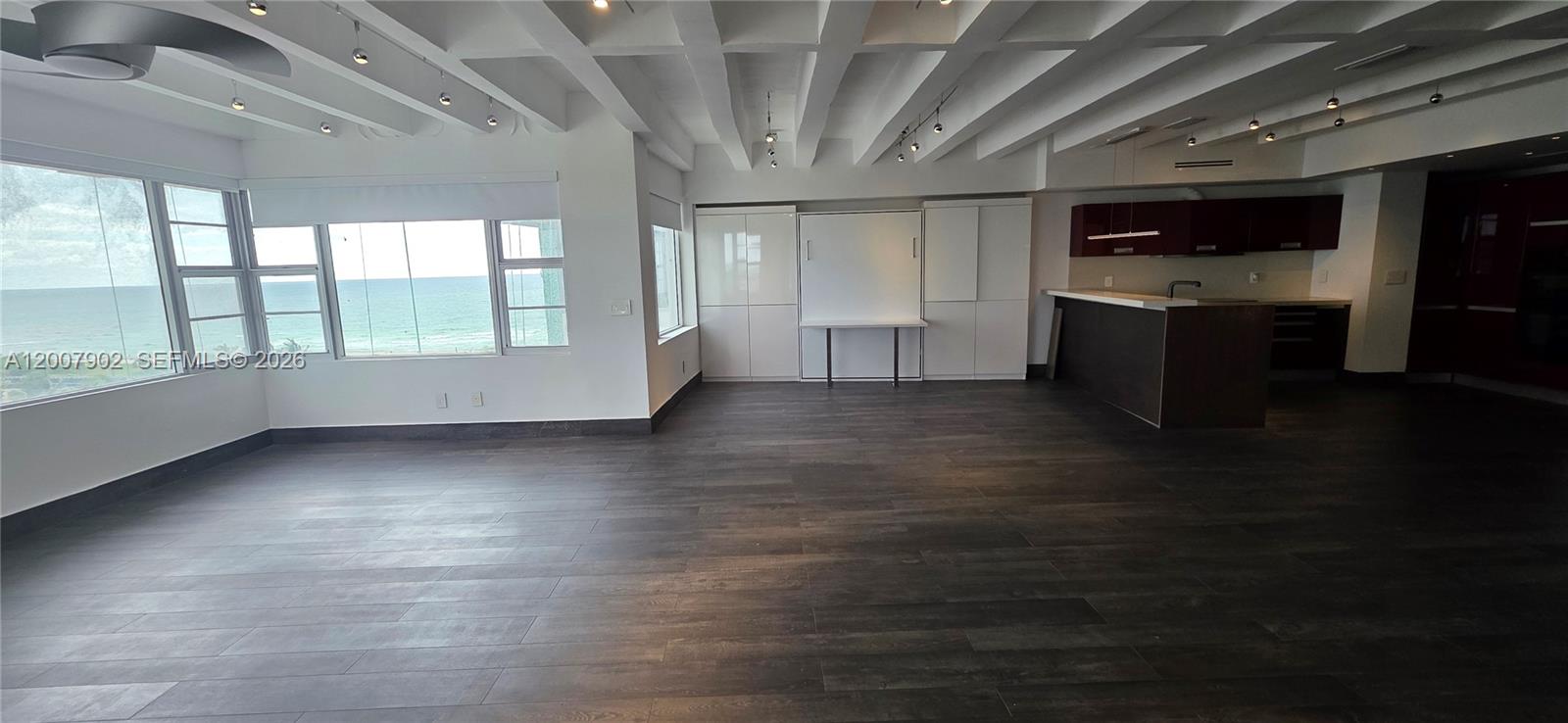A modern living area features dark wood flooring, a coffered ceiling, and ocean views — 5255 Collins Ave # 7G, Miami Beach FL 33140, MIAMI BEACH, FL