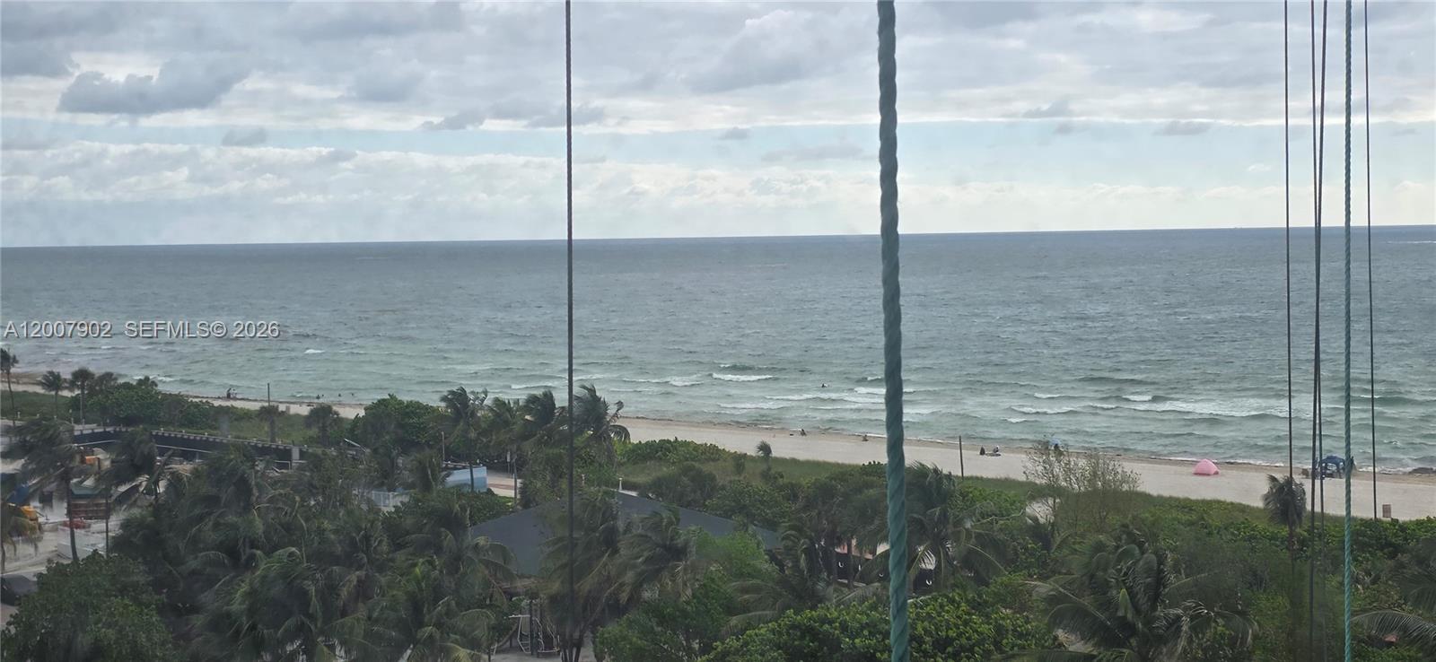An elevated view of a sandy beach and ocean seen through vertical window mullions — 5255 Collins Ave # 7G, Miami Beach FL 33140, MIAMI BEACH, FL