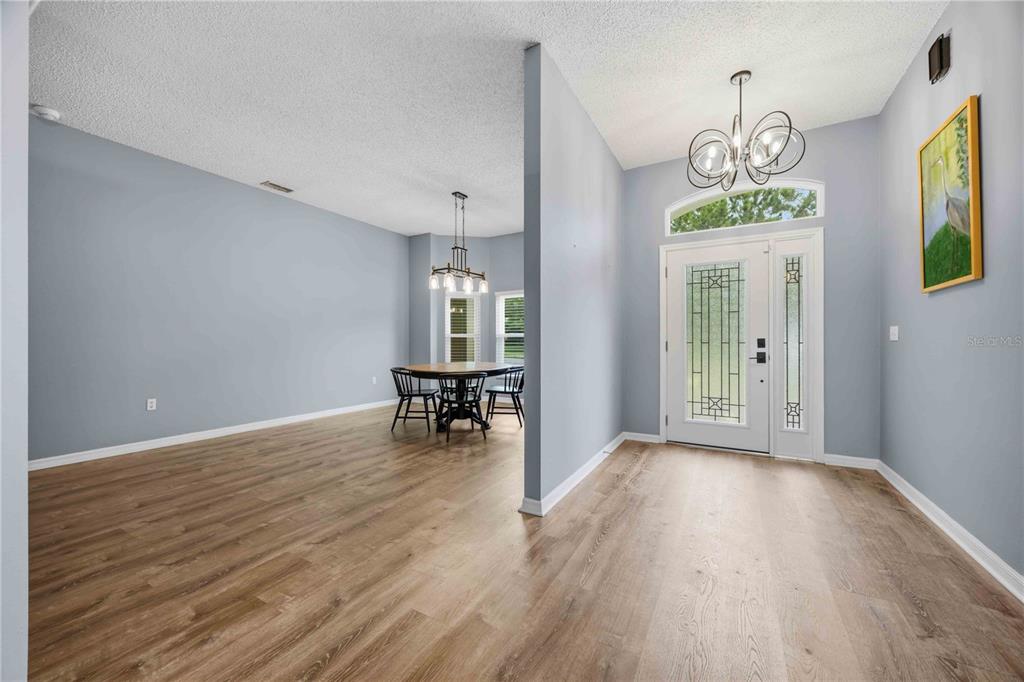 An entryway with light wood flooring leads to a dining area with a round table — 715 JESSANDA CIRCLE, LAKELAND, FL