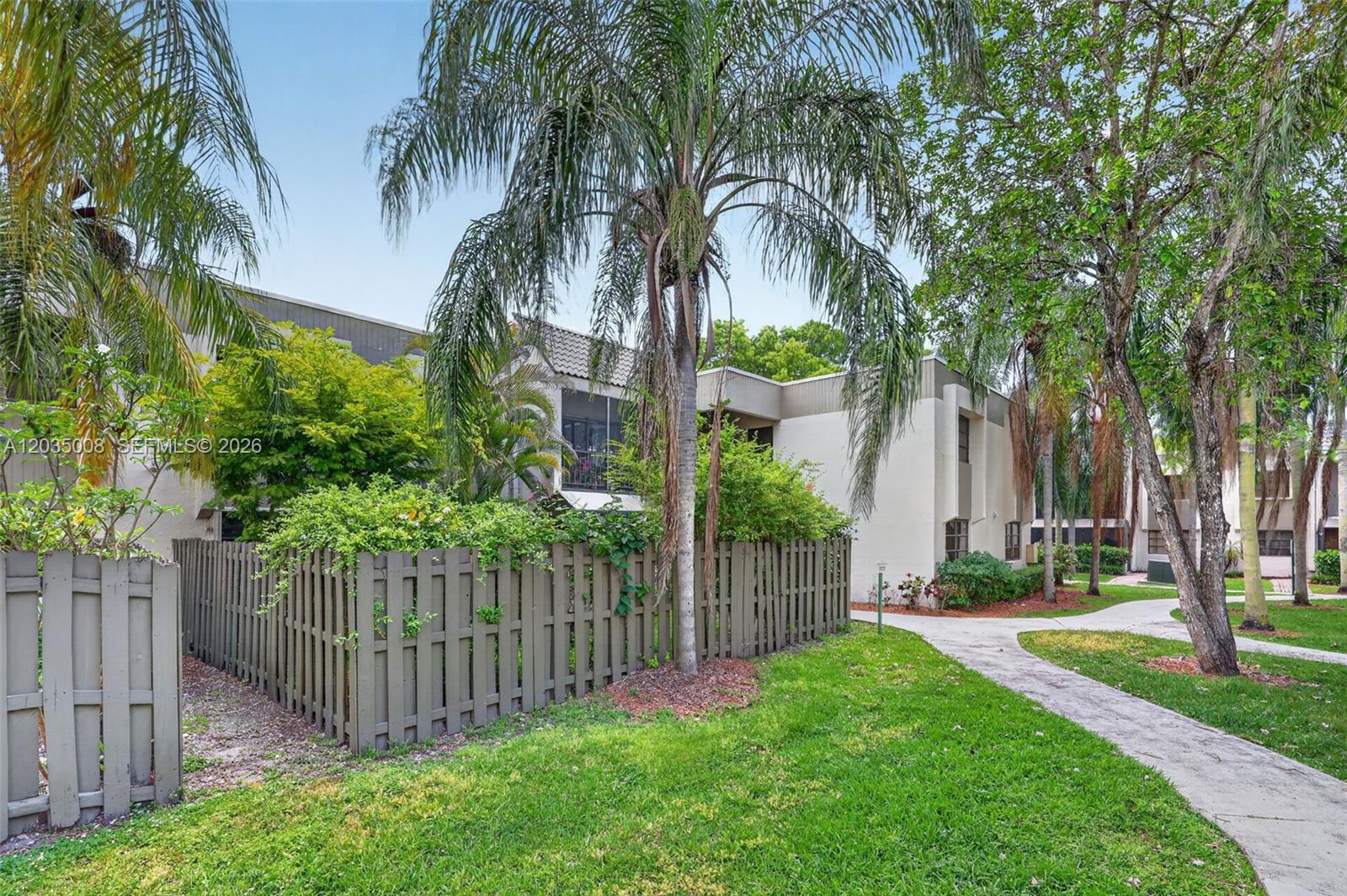 A two-story residential building with a fenced patio area and a concrete walkway — 7917 SW 104th St # 201F, Miami FL 33156, MIAMI, FL