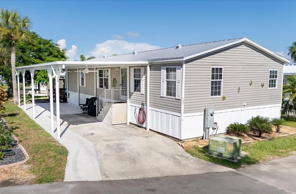 A gray manufactured home with a metal roof, white skirting, and a covered carport — 3127 BAYSIDE PARKWAY, PUNTA GORDA, FL