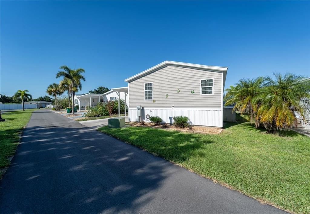 A gray mobile home with a white skirt sits next to a paved driveway — 3127 BAYSIDE PARKWAY, PUNTA GORDA, FL