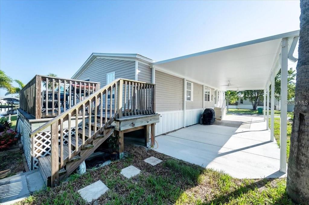 An exterior view of a mobile home with a wooden deck and a covered carport — 3127 BAYSIDE PARKWAY, PUNTA GORDA, FL