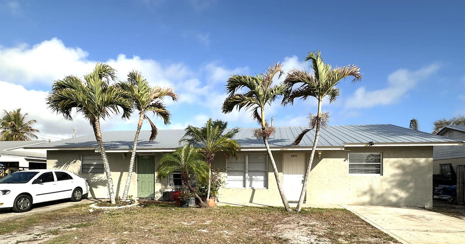 A single-story house with a metal roof, palm trees, and a white car parked outside — 3365 SE Garden Street # 3365, Stuart FL 34997, STUART, FL