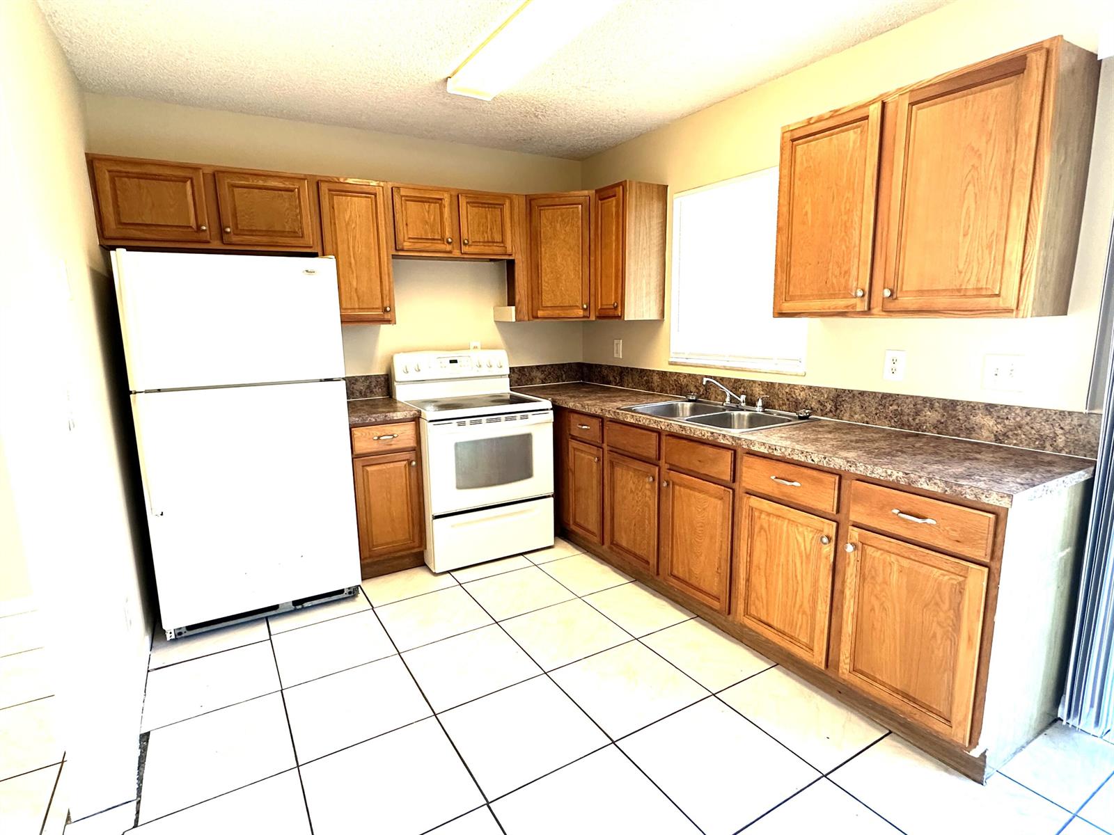 A kitchen features oak cabinets, white appliances, laminate countertops, and white tiled flooring — 3365 SE Garden Street # 3365, Stuart FL 34997, STUART, FL
