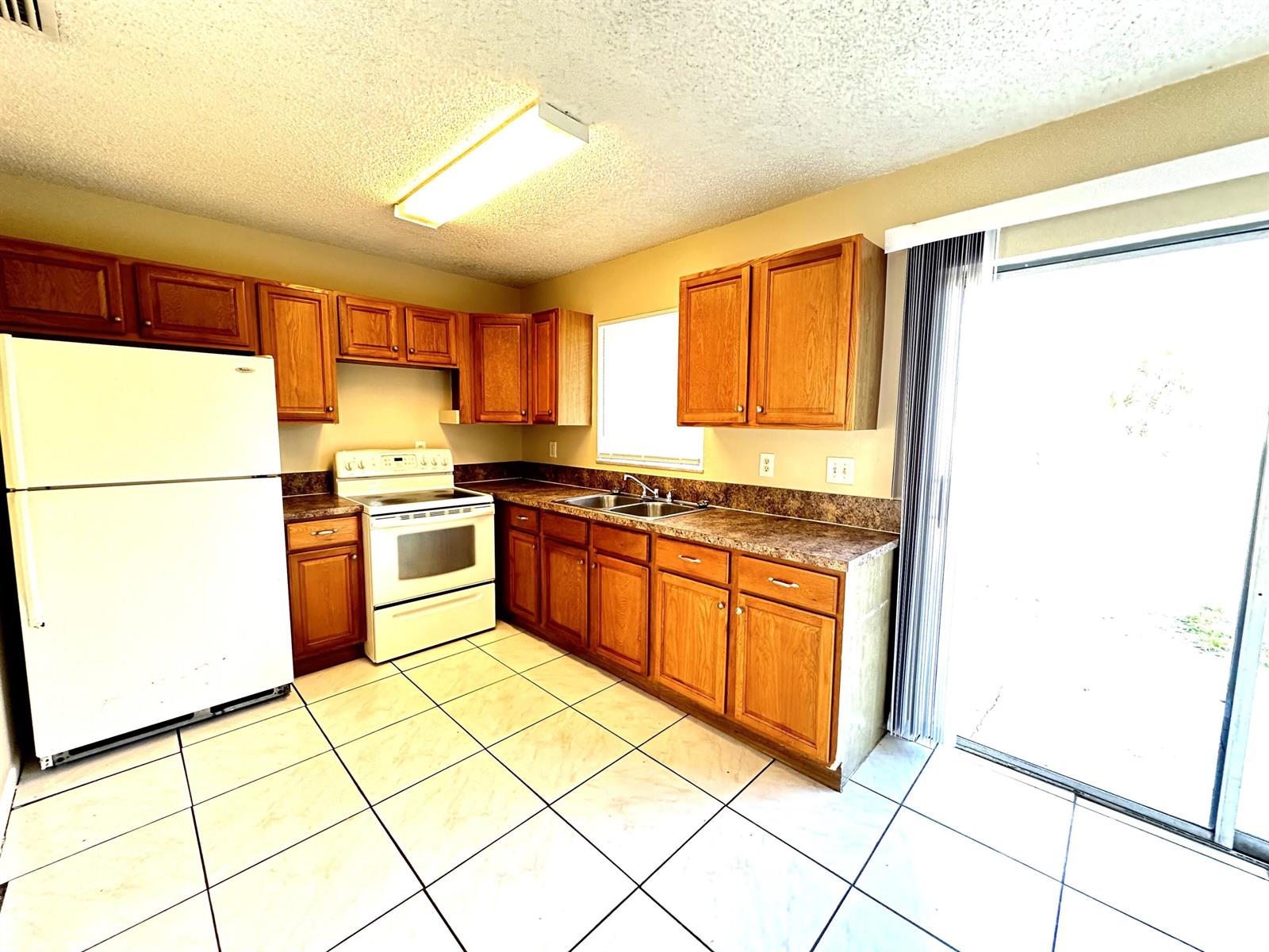 A kitchen features wood cabinets, white appliances, laminate countertops, and light-colored tile flooring — 3365 SE Garden Street # 3365, Stuart FL 34997, STUART, FL